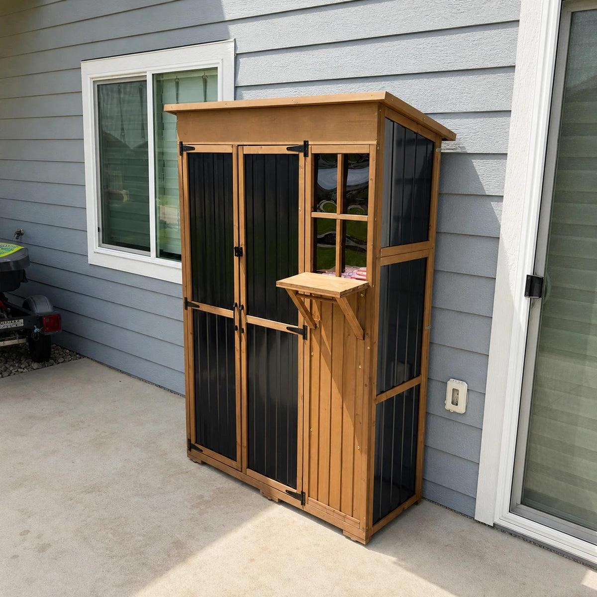 Petscosset tall wooden outdoor storage cabinet with black doors, fold-out desk, and clear window set up on a house patio